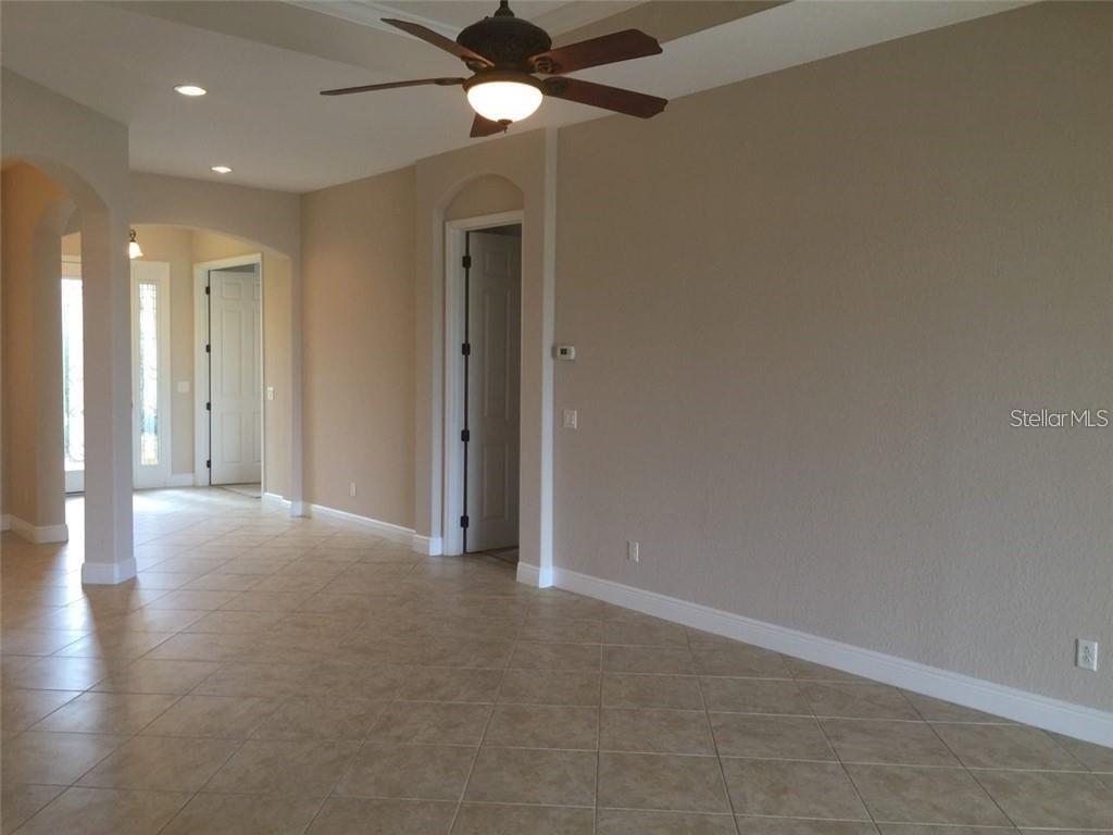 A room with beige walls, tile flooring, a ceiling fan, and several doorways — 5570 ROCK DOVE DRIVE, SARASOTA, FL