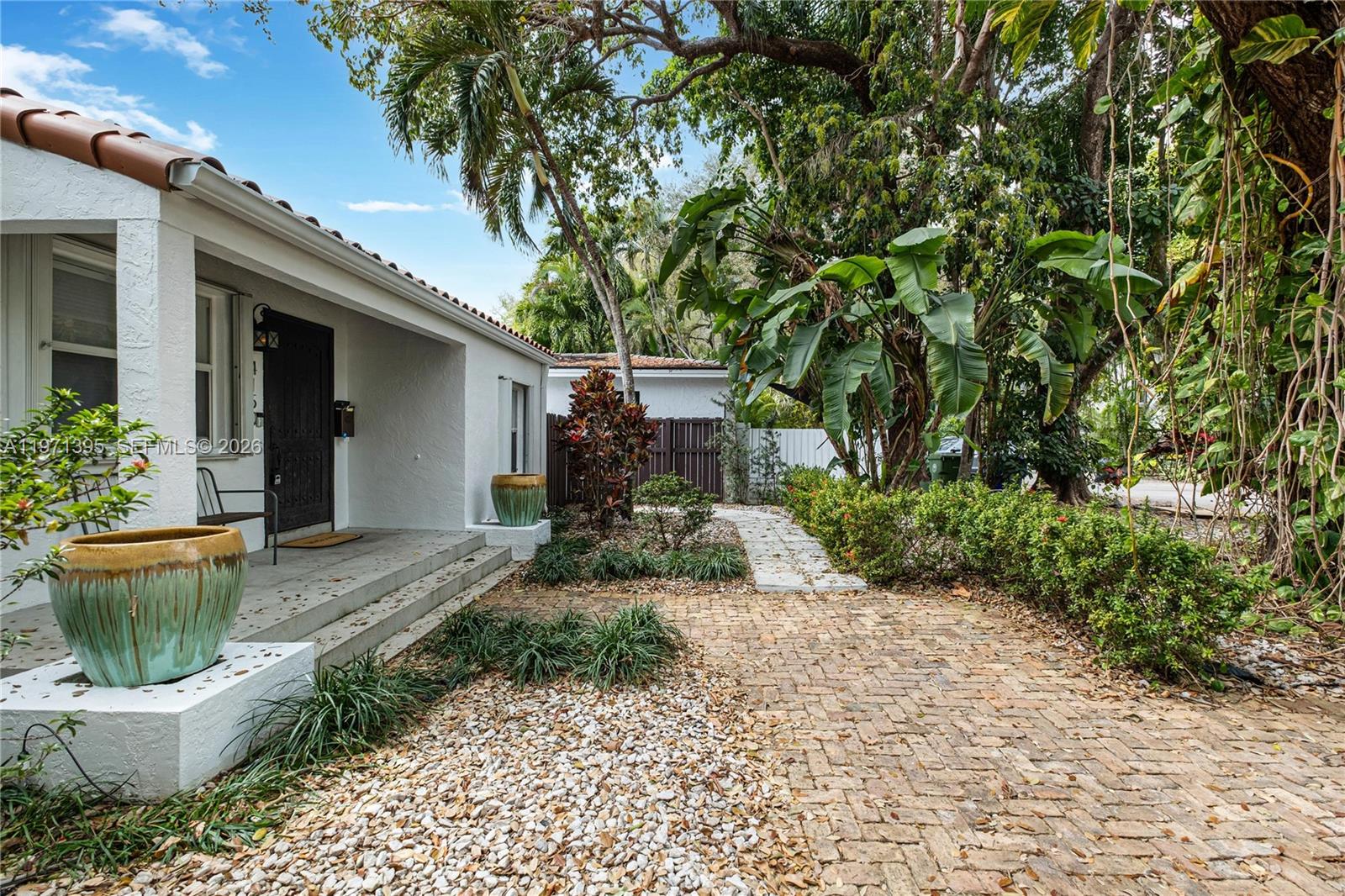 A white house with a brick walkway, a covered porch, and lush tropical landscaping — 4150 Ventura Ave, Miami FL 33133, MIAMI, FL