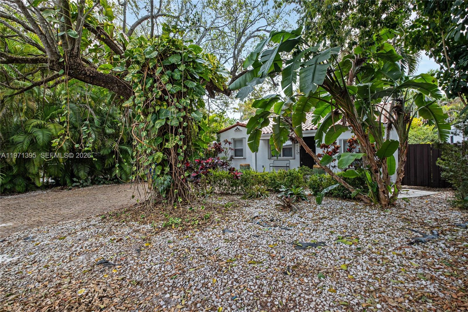 A white house with a tile roof is surrounded by lush tropical landscaping and gravel — 4150 Ventura Ave, Miami FL 33133, MIAMI, FL