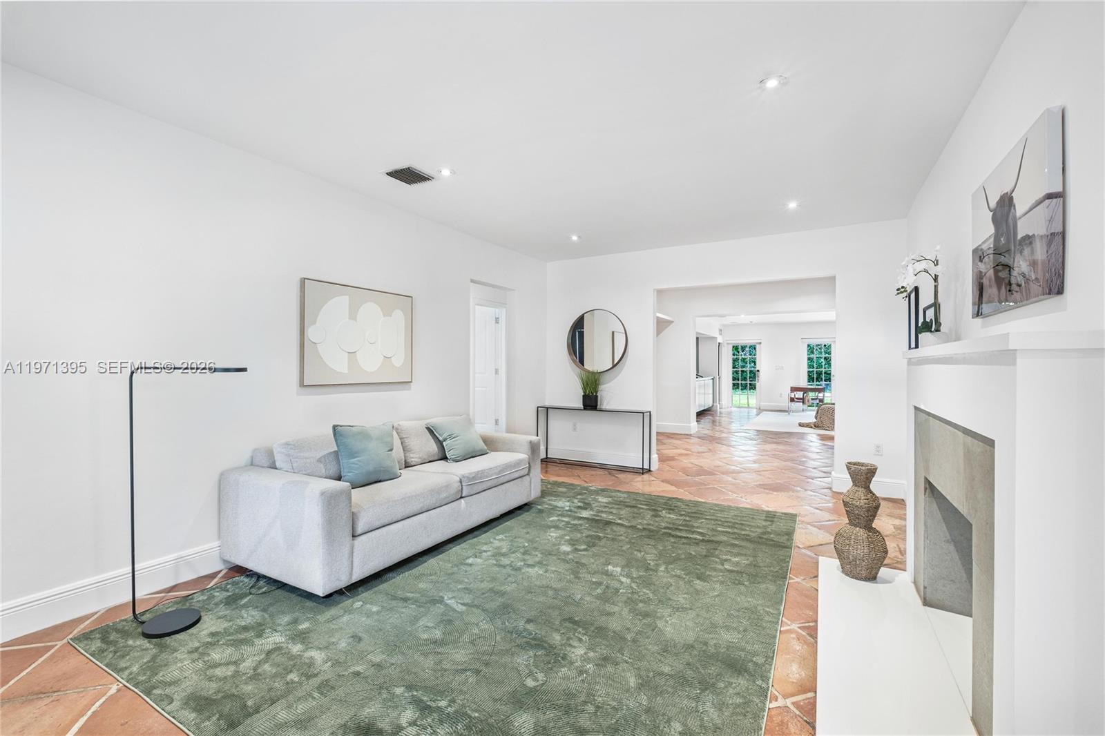 A living room features a grey sofa, a green rug, and a fireplace on tiled floors — 4150 Ventura Ave, Miami FL 33133, MIAMI, FL