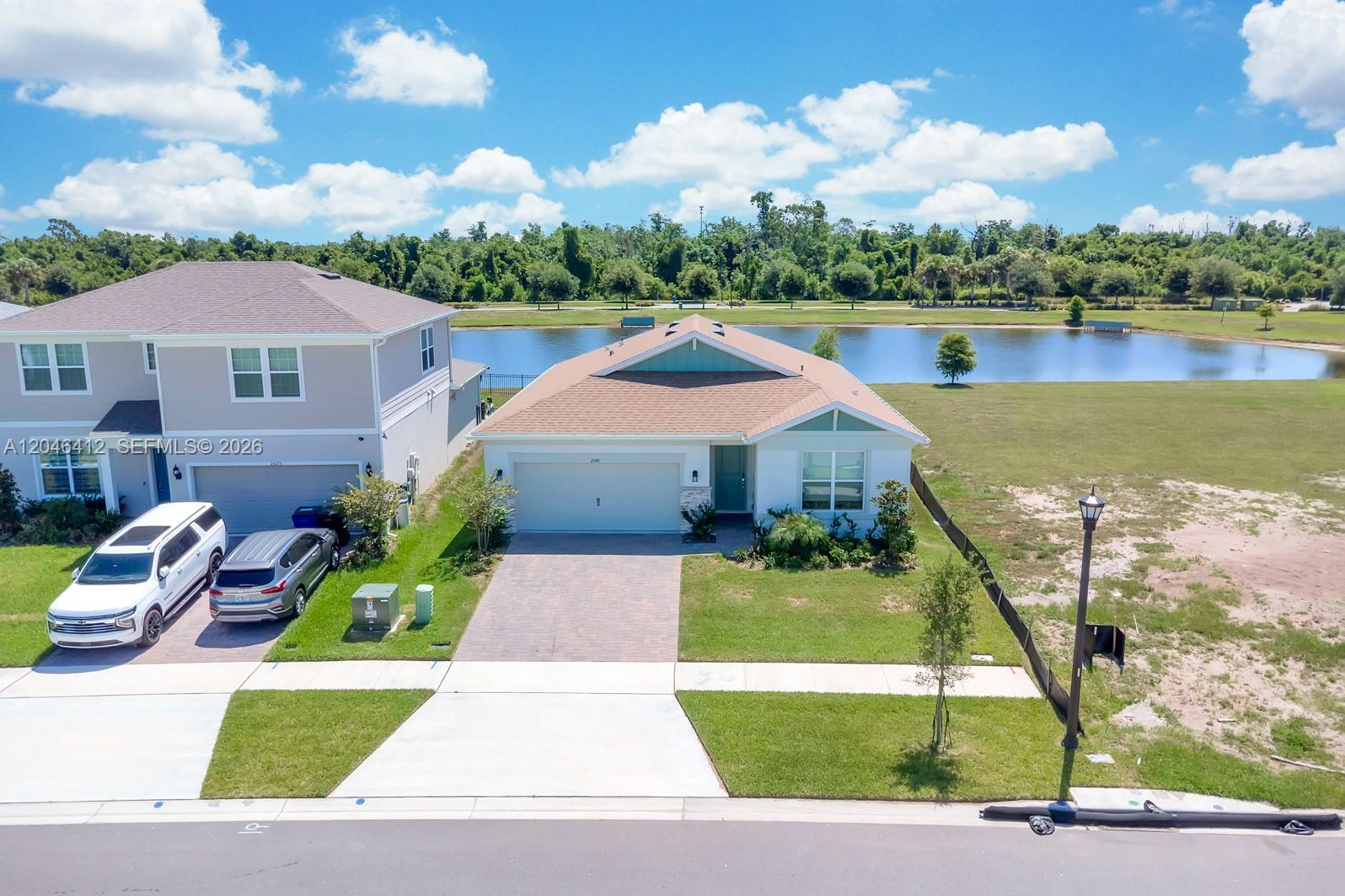 An aerial view shows a single-story house with a paved driveway next to a lake — 2081 MOSSY VINE AV, Saint Cloud FL 34771, SAINT CLOUD, FL