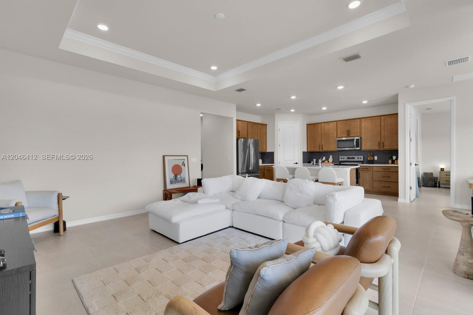 A living room with a white sectional sofa opens into a kitchen with wooden cabinets — 2081 MOSSY VINE AV, Saint Cloud FL 34771, SAINT CLOUD, FL
