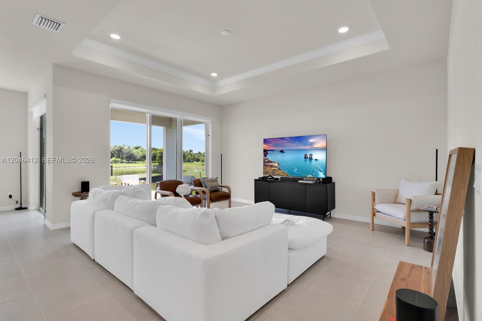 A living room features a white sectional sofa, a television on a black console, and large sliding doors — 2081 MOSSY VINE AV, Saint Cloud FL 34771, SAINT CLOUD, FL