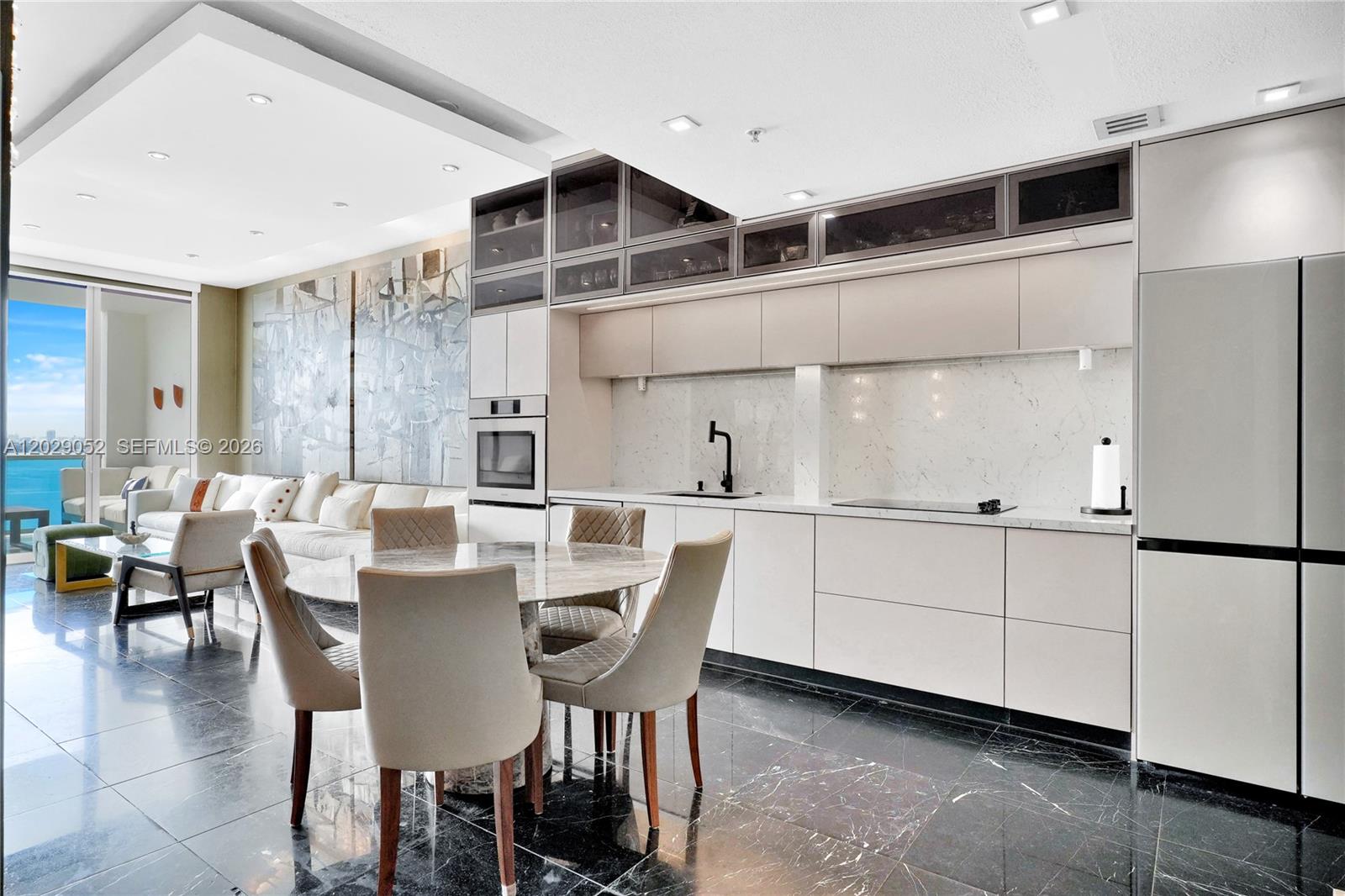 A modern kitchen and dining area feature marble floors, light cabinetry, and ocean views — 725 NE 22nd St # 11E, Miami FL 33137, MIAMI, FL
