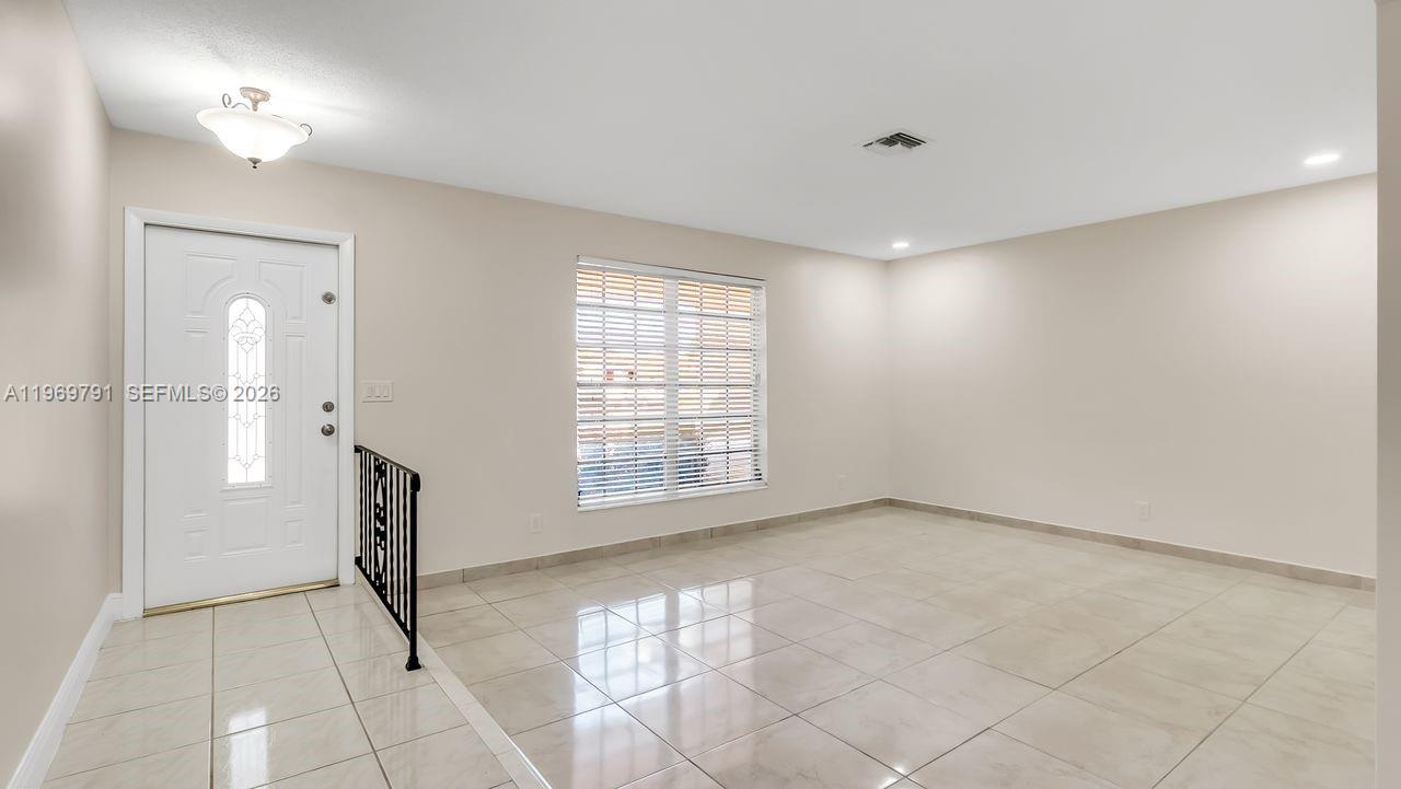 An empty room with light-colored tile flooring, a front door, and a window with blinds — 5300 Grant St, Hollywood FL 33021, HOLLYWOOD, FL