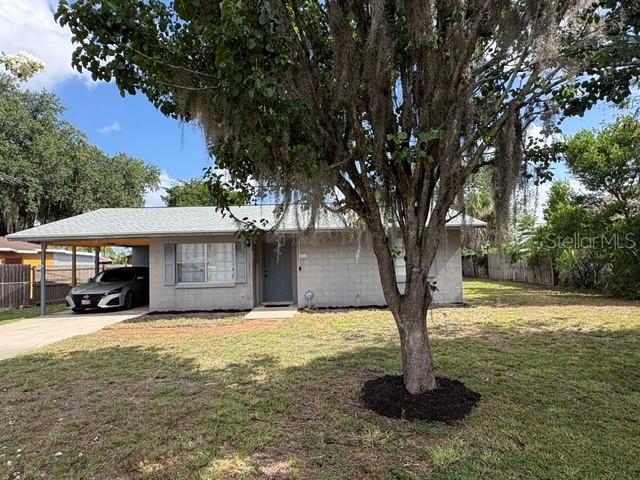 A single-story house with a carport and a large tree in the front yard — 506 W 9TH STREET, FROSTPROOF, FL