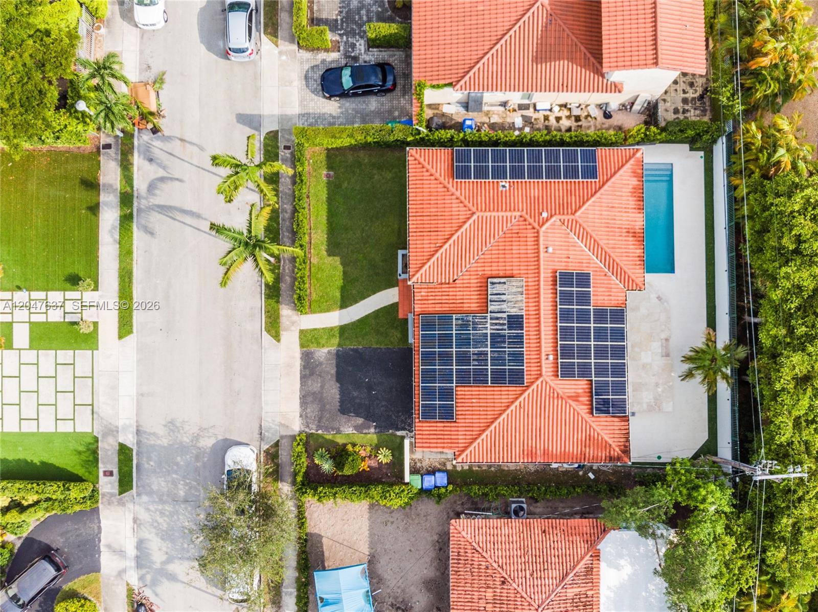An aerial view shows a house with solar panels on a red tile roof and a pool — 3504 Crystal View Ct # 0, Miami FL 33133, MIAMI, FL