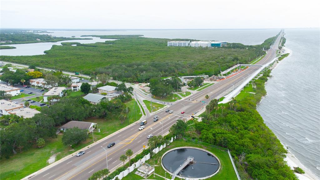 An aerial view shows a coastal road, a circular water treatment tank, and surrounding vegetation — 389 S MCMULLEN BOOTH ROAD UNIT 12, CLEARWATER, FL
