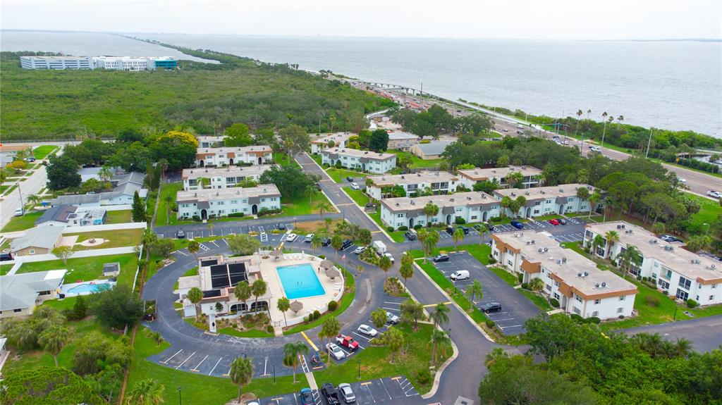 An aerial view shows a multi-building apartment complex with a central swimming pool and parking — 389 S MCMULLEN BOOTH ROAD UNIT 12, CLEARWATER, FL