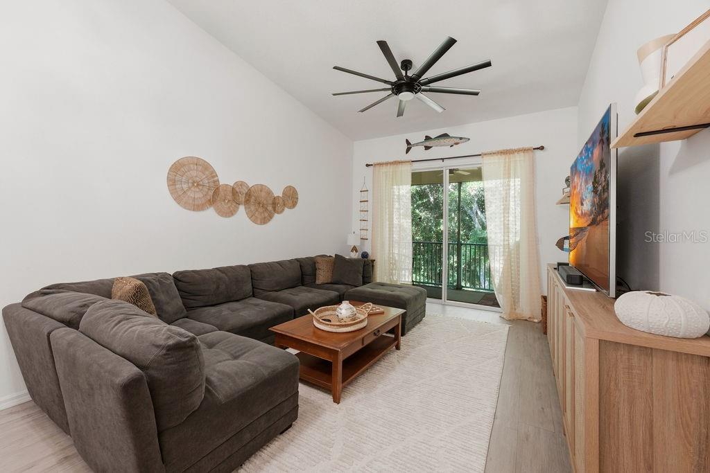 A living room features a large gray sectional sofa, a wooden coffee table, and a television — 90 SAN JUAN DRIVE UNIT B202, PALM COAST, FL