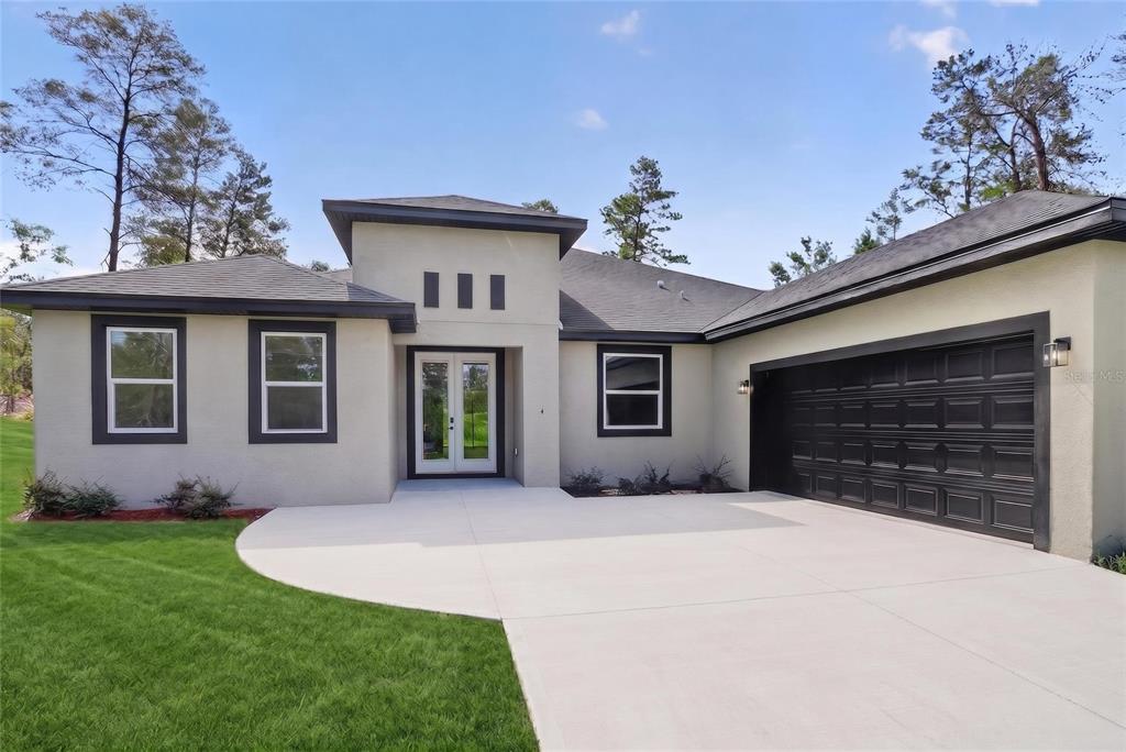 A single-story house with a beige stucco exterior, dark trim, and a two-car garage — 4 LONE PINE STREET, HOMOSASSA, FL