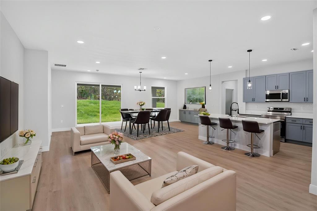 An open-concept living, dining, and kitchen area with light wood floors and blue cabinetry — 4 LONE PINE STREET, HOMOSASSA, FL