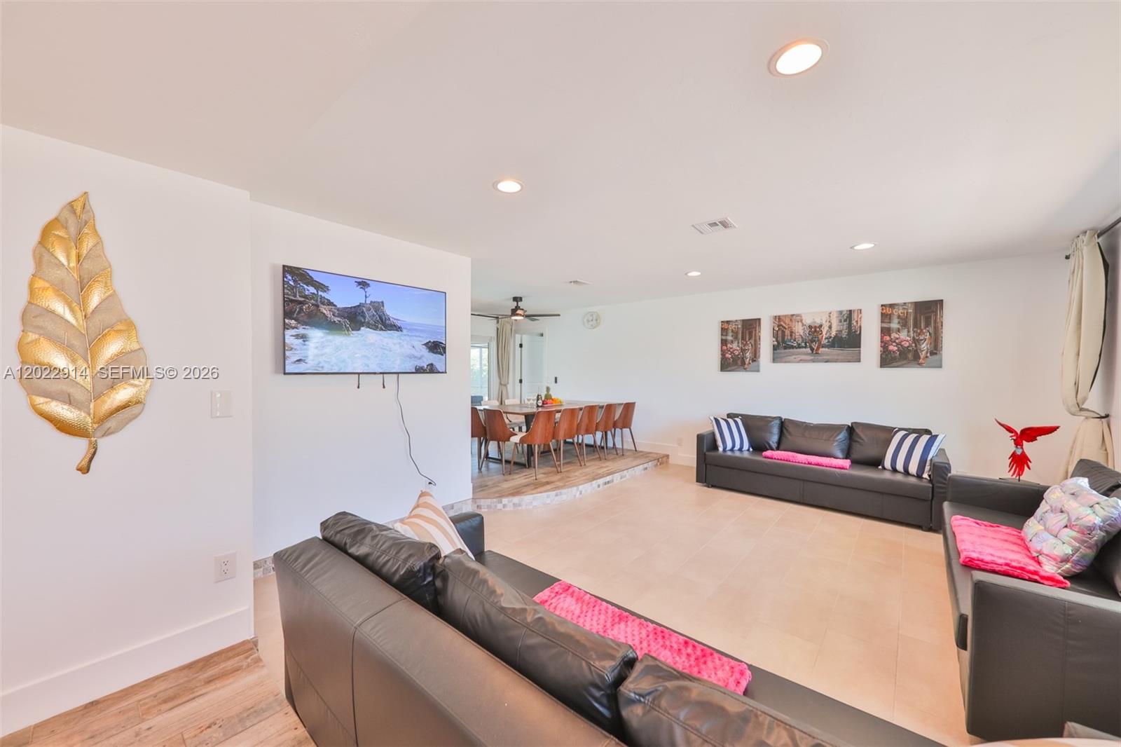 A living room features black leather sofas, a wall-mounted television, and an adjacent dining area — 209 Bayshore Dr, Cape Coral FL 33904, CAPE CORAL, FL
