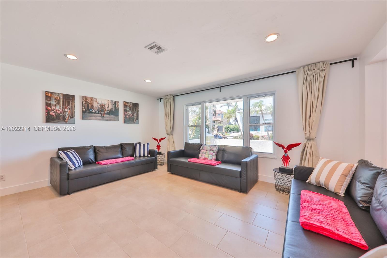 A living room features three black leather sofas, tile flooring, and large windows with curtains — 209 Bayshore Dr, Cape Coral FL 33904, CAPE CORAL, FL