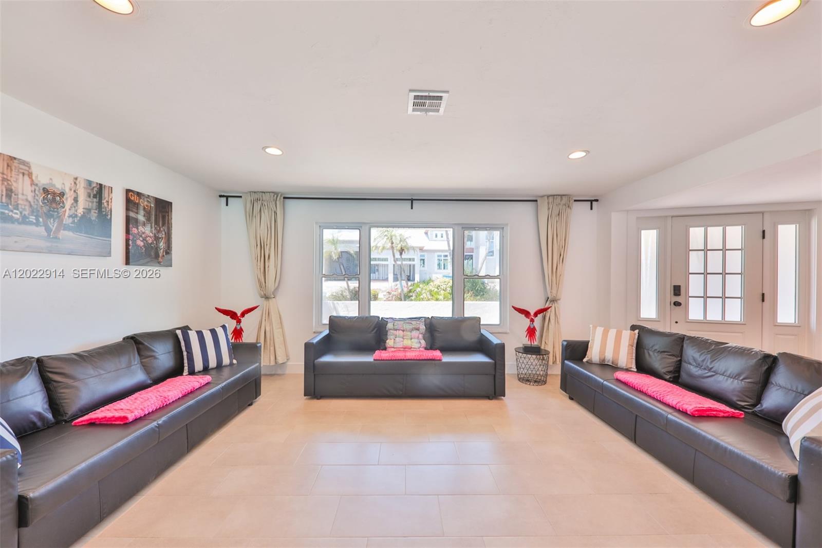 A living room features three black leather sofas, tile flooring, and a large central window — 209 Bayshore Dr, Cape Coral FL 33904, CAPE CORAL, FL