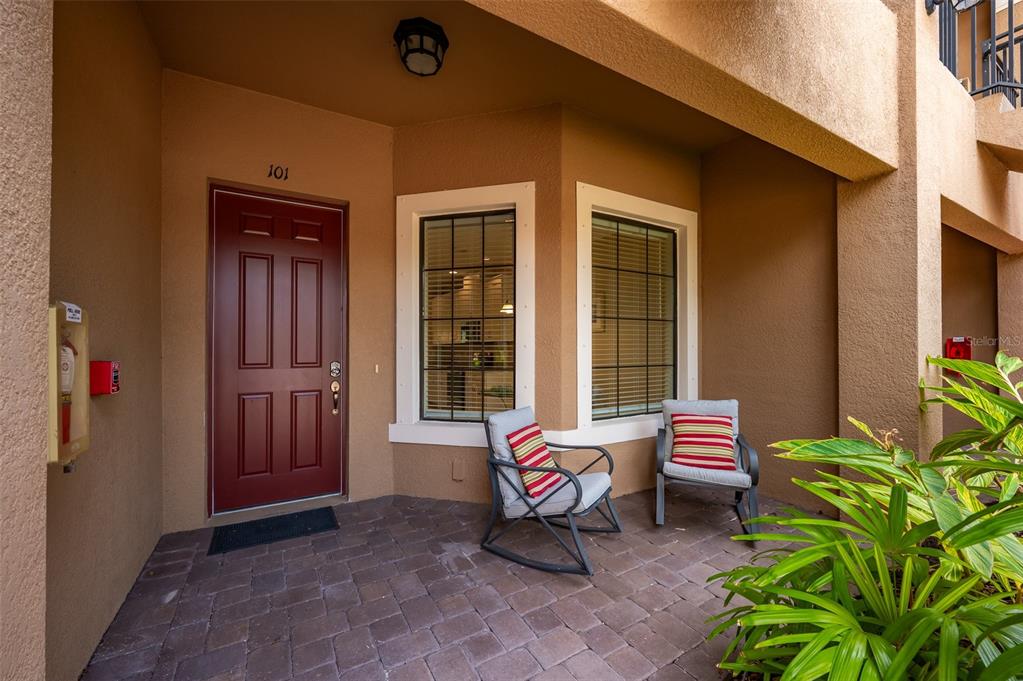 A covered patio entrance features a red door, two chairs, and a paved floor — 5425 CICERONE STREET UNIT 101, SARASOTA, FL
