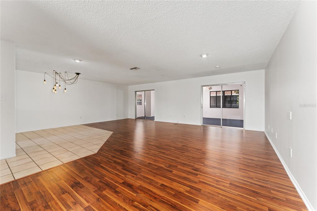 An open-concept living area features wood-look flooring, a tiled entryway, and sliding glass doors — 10823 WILLIAM AND MARY COURT, ORLANDO, FL