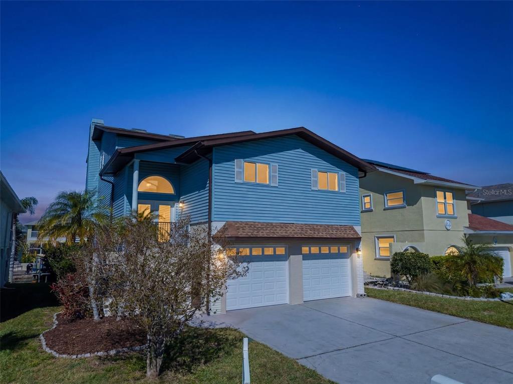 A two-story blue house with a two-car garage and a front-facing balcony at dusk — 6241 BAYSIDE DRIVE, NEW PORT RICHEY, FL