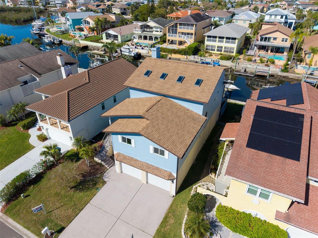 An aerial view shows a light blue two-story house with a brown roof and skylights — 6241 BAYSIDE DRIVE, NEW PORT RICHEY, FL