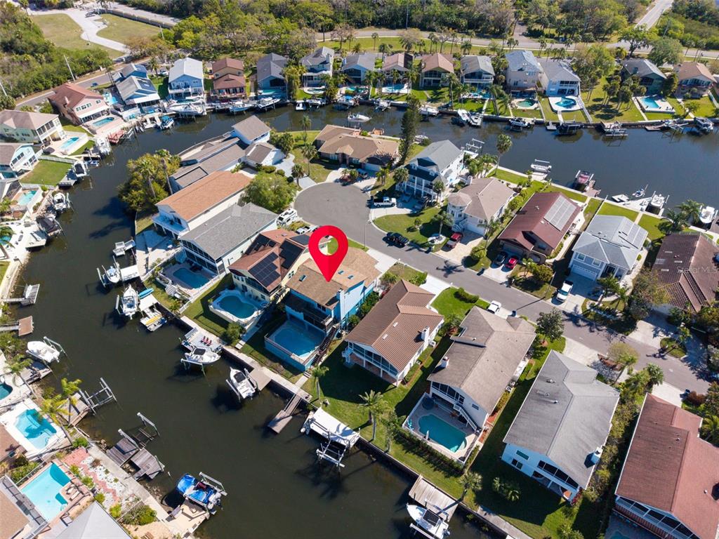 An aerial view shows a waterfront house with a pool and boat dock — 6241 BAYSIDE DRIVE, NEW PORT RICHEY, FL