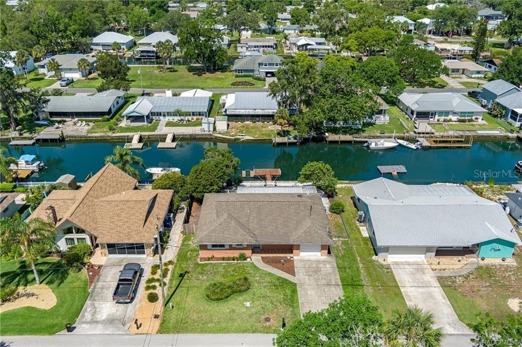 An aerial view shows three houses along a canal with private docks and boats — 1400 SE 5TH AVENUE, CRYSTAL RIVER, FL