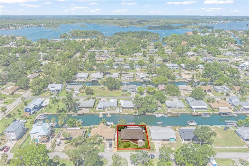 An aerial view shows a single-story house with a red roof along a canal — 1400 SE 5TH AVENUE, CRYSTAL RIVER, FL
