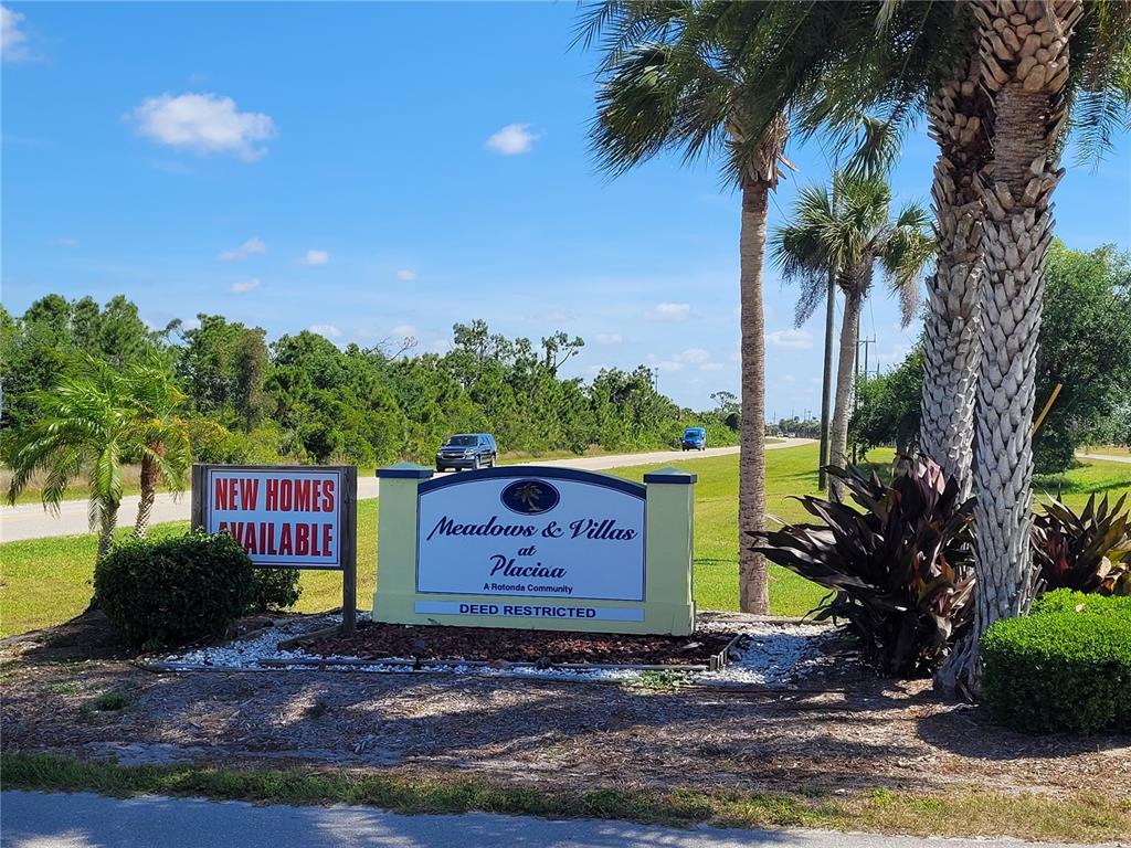 A sign for Meadows & Villas at Placiaa stands near a road with palm trees — 12076 SEA-ROBIN LANE, PLACIDA, FL