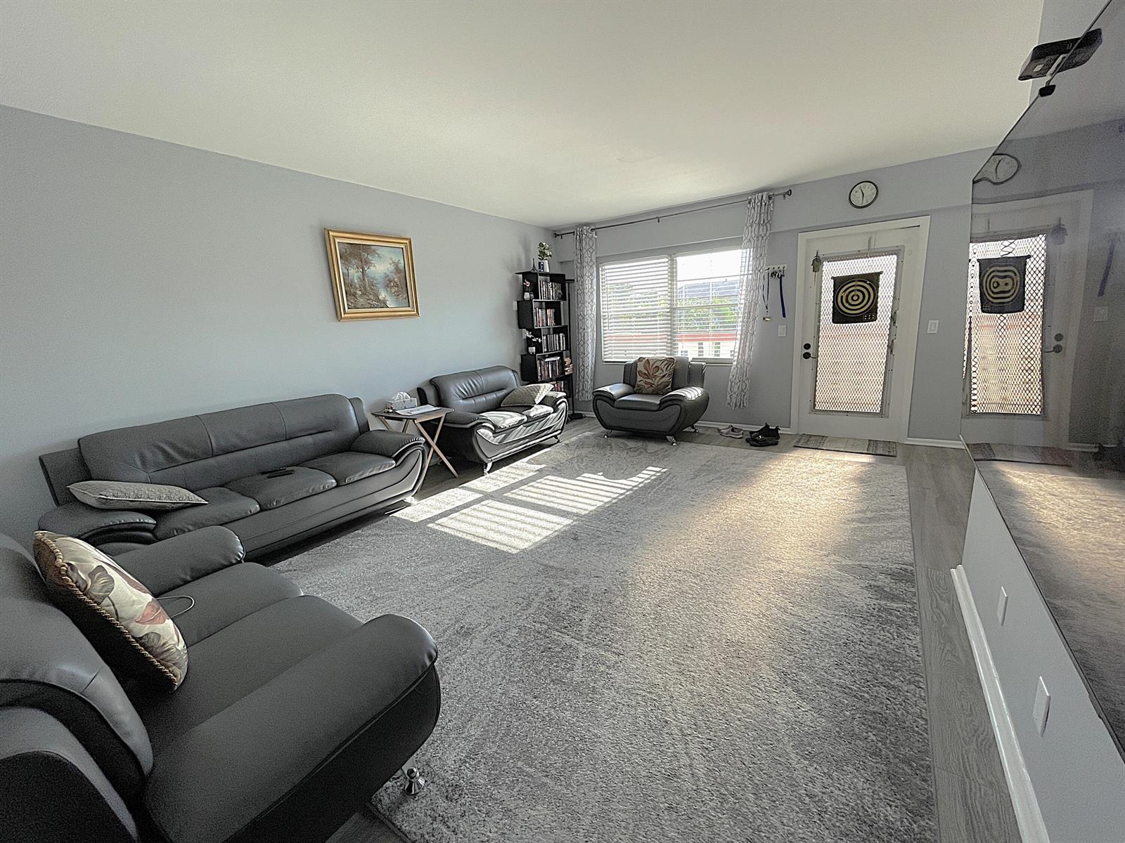 A living room with gray leather sofas, a large area rug, and a front door — 334 Brighton H, Boca Raton FL 33434, BOCA RATON, FL