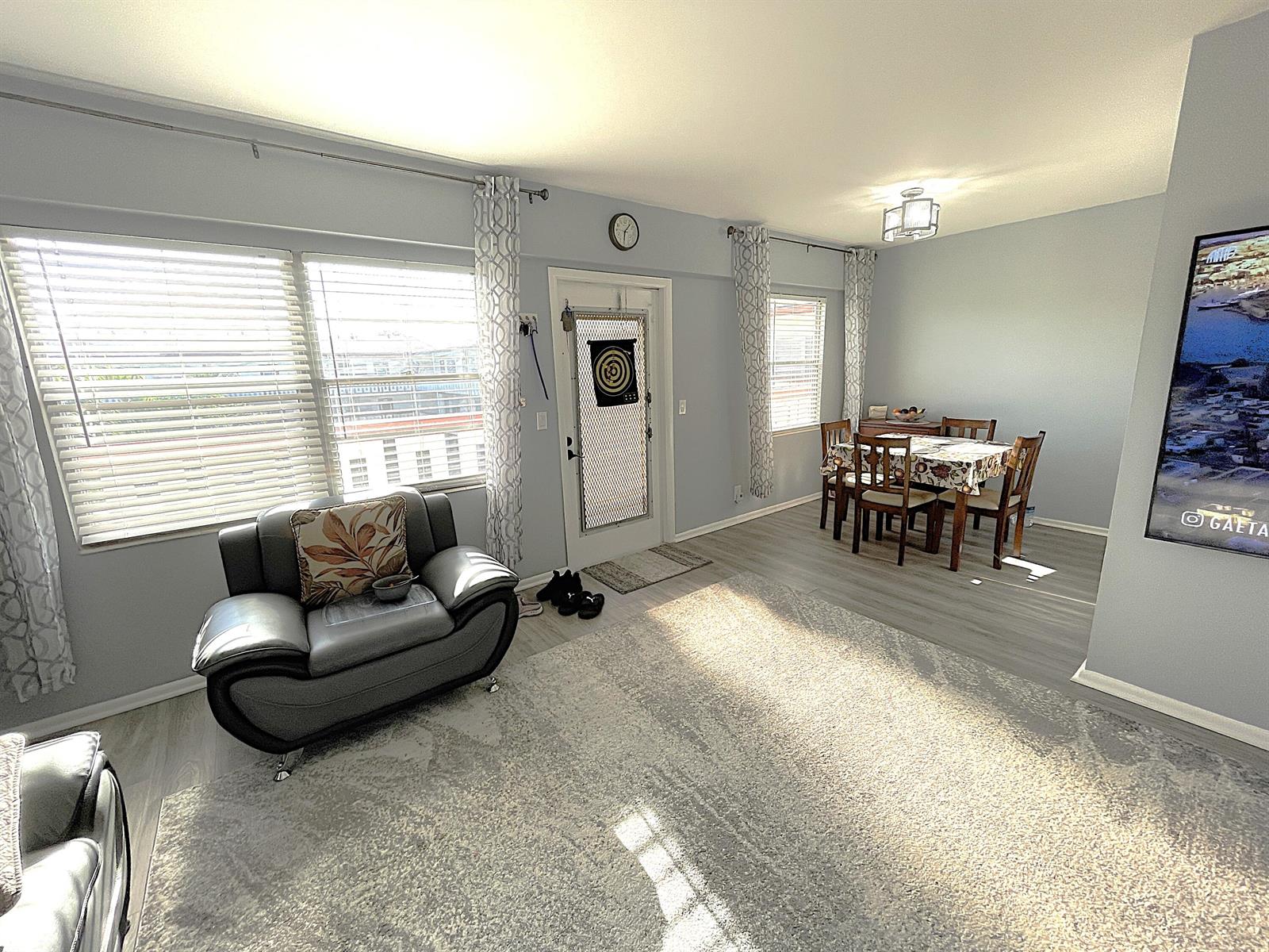 A living room with a gray armchair, a dining set, and a front door — 334 Brighton H, Boca Raton FL 33434, BOCA RATON, FL
