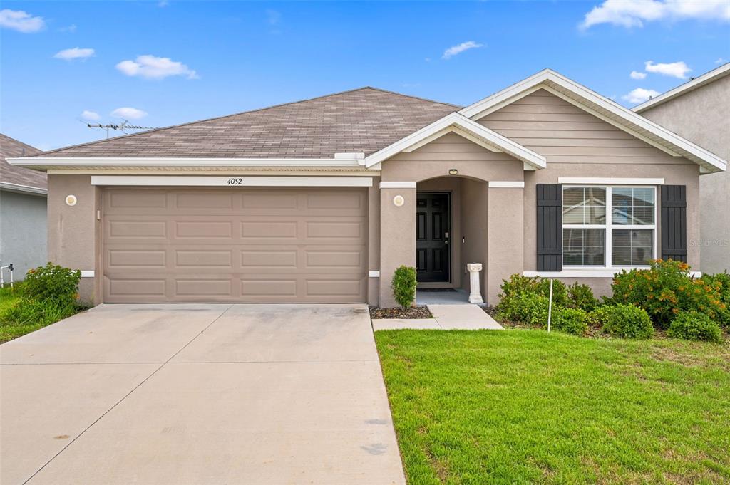 A single-story house with a beige stucco exterior, a two-car garage, and a front lawn — 4052 AUTUMN AMBER DRIVE, SPRING HILL, FL