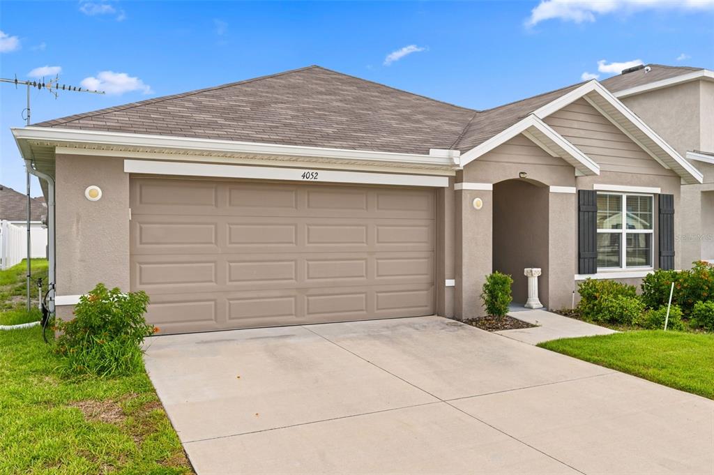A single-story house with a beige stucco exterior, a two-car garage, and a front entrance — 4052 AUTUMN AMBER DRIVE, SPRING HILL, FL