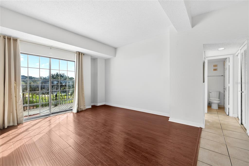 A room with wood-look tile flooring, white walls, and a sliding glass door to a balcony — 235 6TH STREET NW UNIT 307, WINTER HAVEN, FL