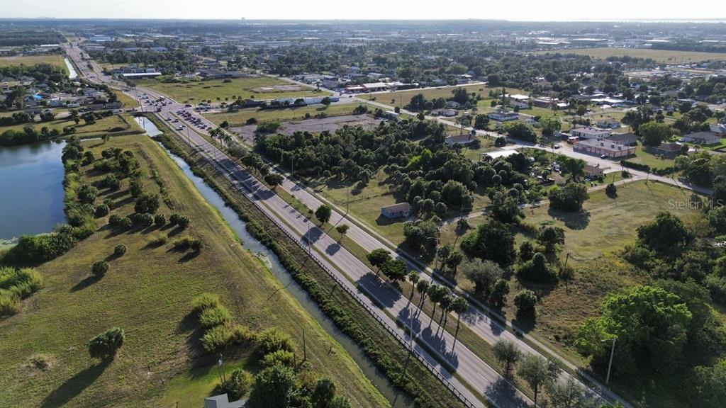 An aerial view shows a multi-lane road running alongside a canal near undeveloped land — 3550 S GRIMSLEY COURT, FORT MYERS, FL