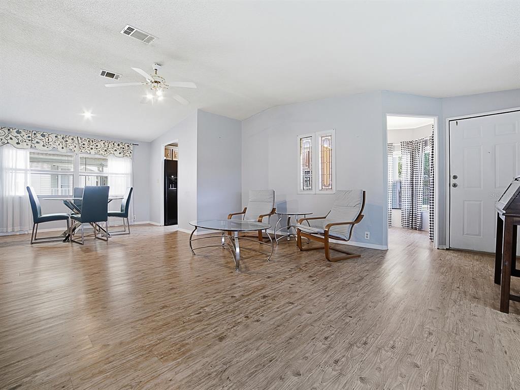 An open-concept living and dining area features light wood-look flooring and a ceiling fan — 25035 BELLEVUE, LEESBURG, FL