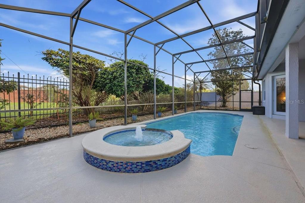 A screened-in patio features a swimming pool with an attached circular spa and fountain — 10926 WOODCHASE CIRCLE, ORLANDO, FL