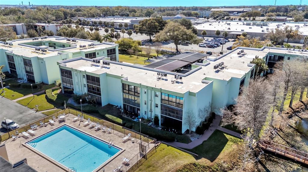 An aerial view shows a multi-story apartment complex with a swimming pool and parking lot — 1130 N LAKE PARKER AVENUE UNIT A109, LAKELAND, FL