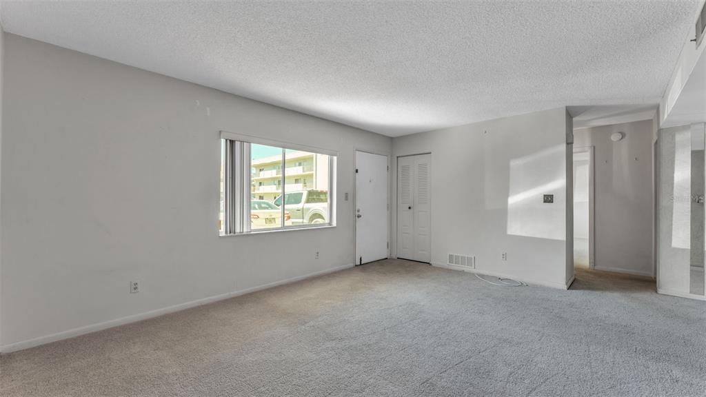 An empty living room with gray carpet, white walls, a window, and a white door — 1130 N LAKE PARKER AVENUE UNIT A109, LAKELAND, FL