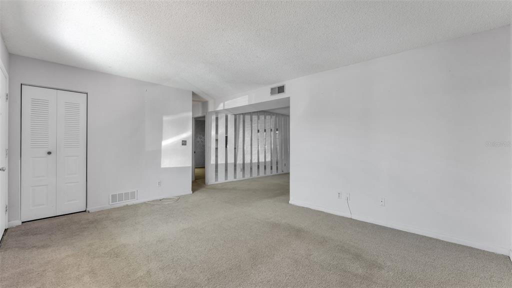 An empty room features beige carpeting, white walls, a white closet door, and a slatted partition — 1130 N LAKE PARKER AVENUE UNIT A109, LAKELAND, FL