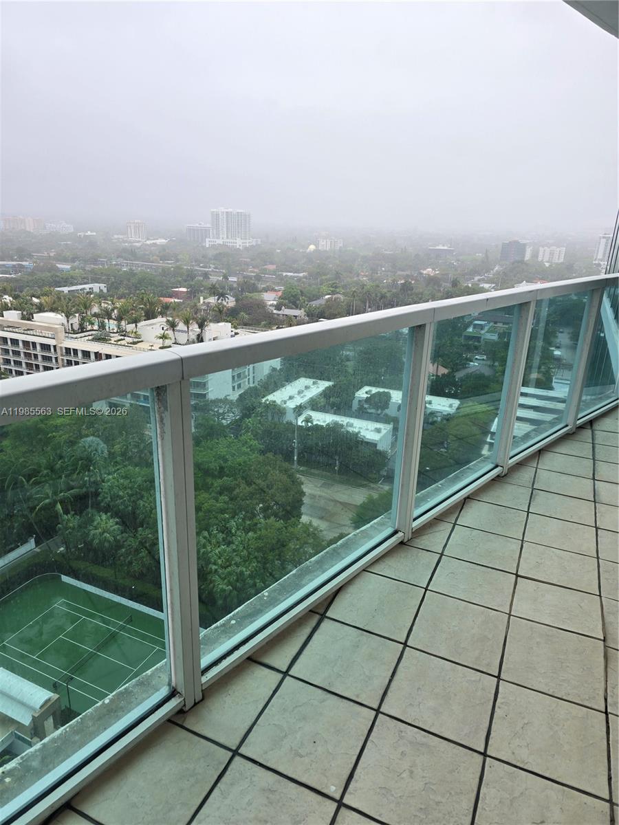 A high-rise balcony with a glass railing overlooks a tennis court and urban landscape — 2101 Brickell Ave # 1911, Miami FL 33129, MIAMI, FL