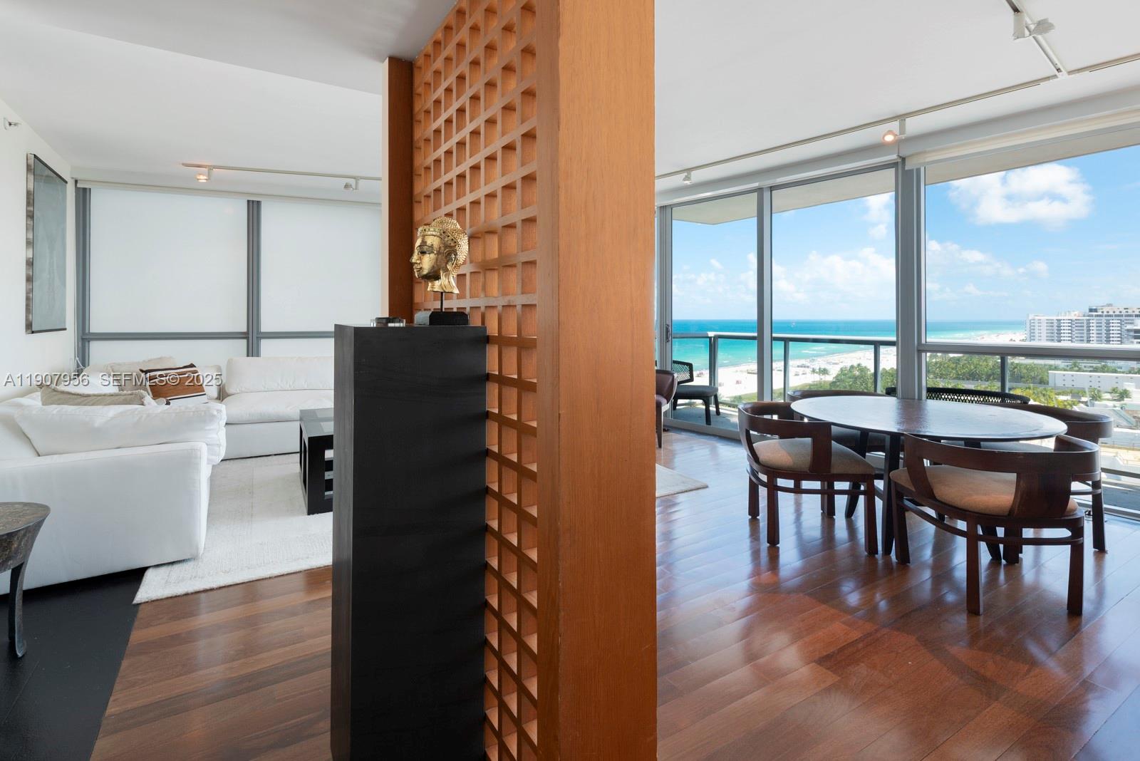 A living and dining area features a wooden room divider, hardwood floors, and ocean views — 101 20th St # 2004, Miami Beach FL 33139, MIAMI BEACH, FL