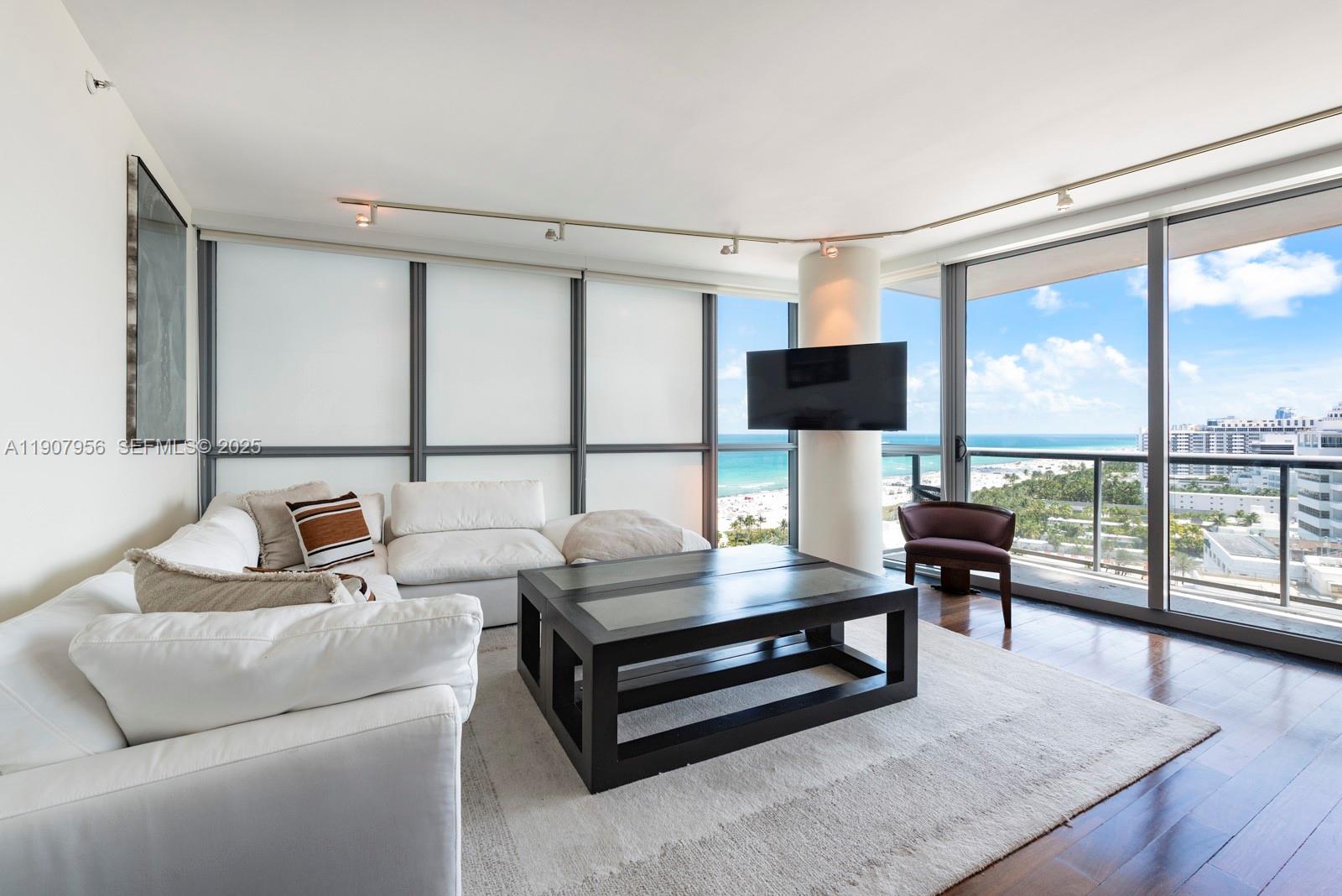 A living room features a white sectional sofa, a dark coffee table, and ocean views — 101 20th St # 2004, Miami Beach FL 33139, MIAMI BEACH, FL