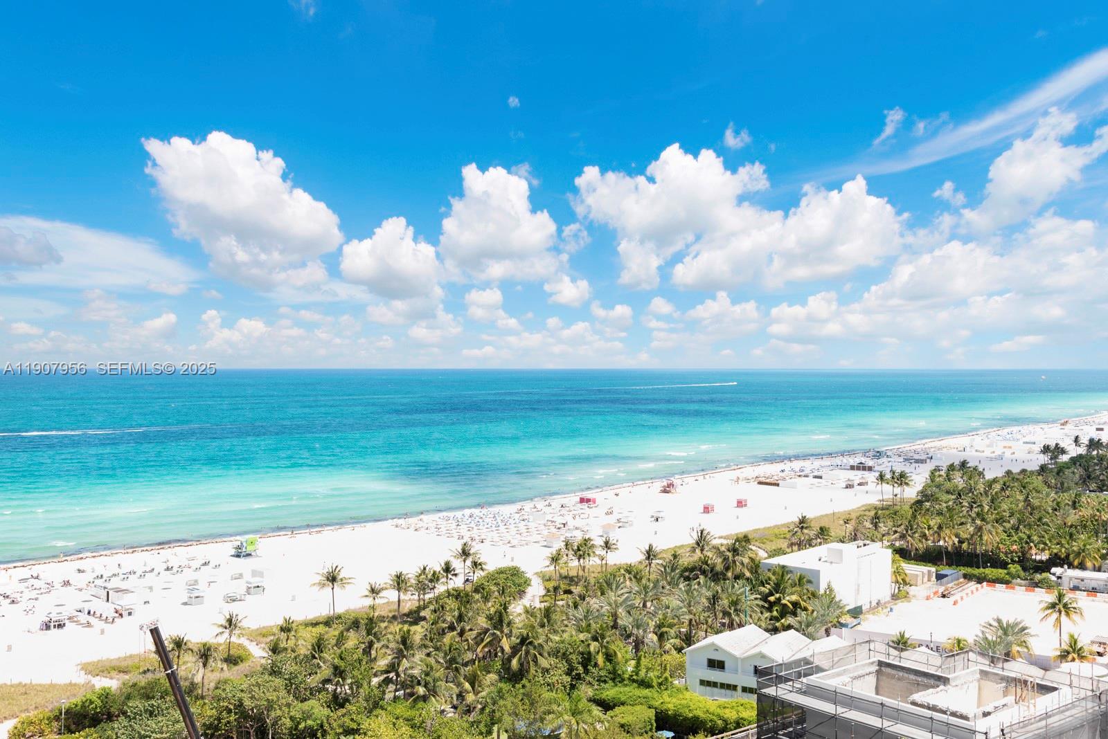 An elevated view of a sandy beach with palm trees and the ocean under clouds — 101 20th St # 2004, Miami Beach FL 33139, MIAMI BEACH, FL