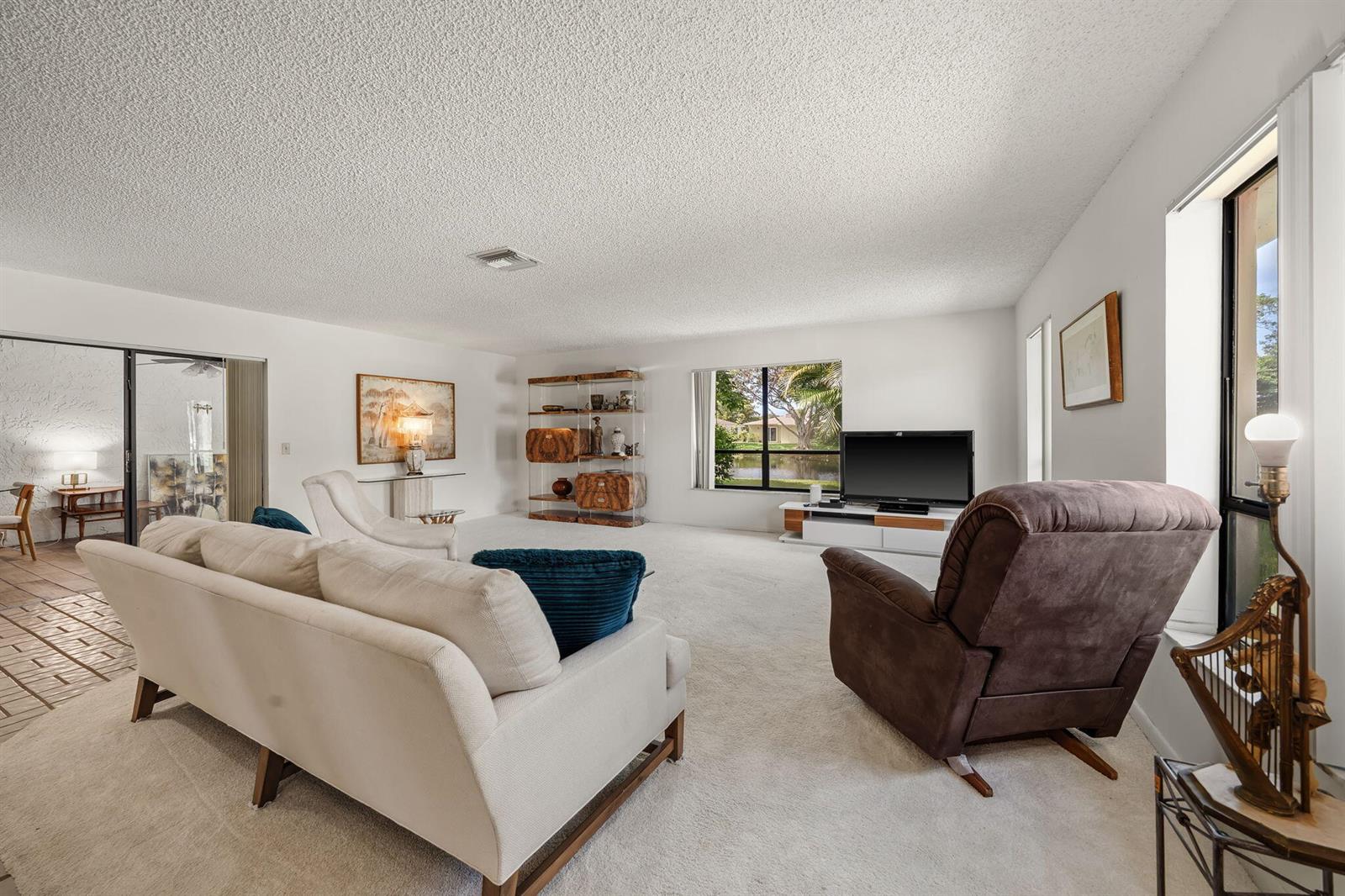 A living room with white carpet, a white sofa, a brown recliner, and a television — 7543 Volley Place, Lake Worth FL 33467, LAKE WORTH, FL