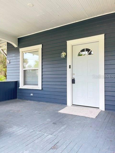A covered porch features dark blue horizontal siding, a white front door, and a window — 143 N STONE STREET UNIT N, DELAND, FL