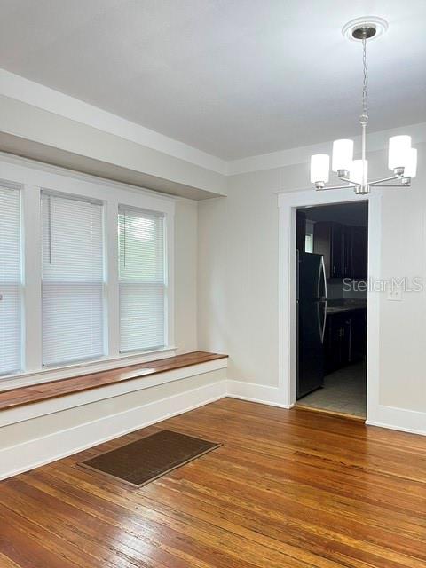 A dining room features hardwood floors, a window seat, and a modern chandelier — 143 N STONE STREET UNIT N, DELAND, FL