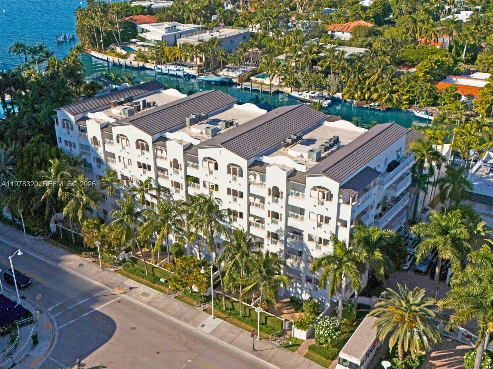 An aerial view shows a multi-story white apartment building situated along a canal — 1415 Sunset Harbour Dr # 202, Miami Beach FL 33139, MIAMI BEACH, FL