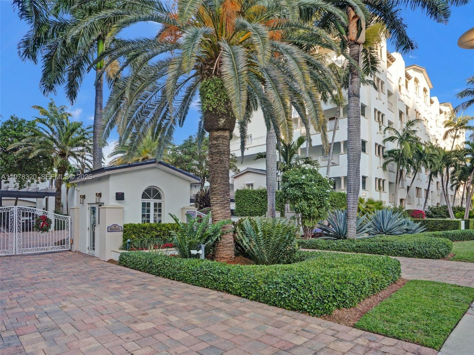 A gated entrance with a guardhouse, palm trees, and a multi-story building in the background — 1415 Sunset Harbour Dr # 202, Miami Beach FL 33139, MIAMI BEACH, FL