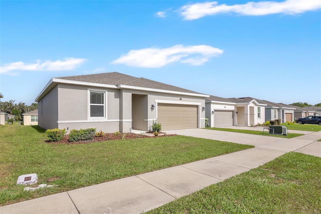 A single-story suburban house with a tan garage and light-colored stucco exterior — 3526 FORSTER AVENUE, LEESBURG, FL