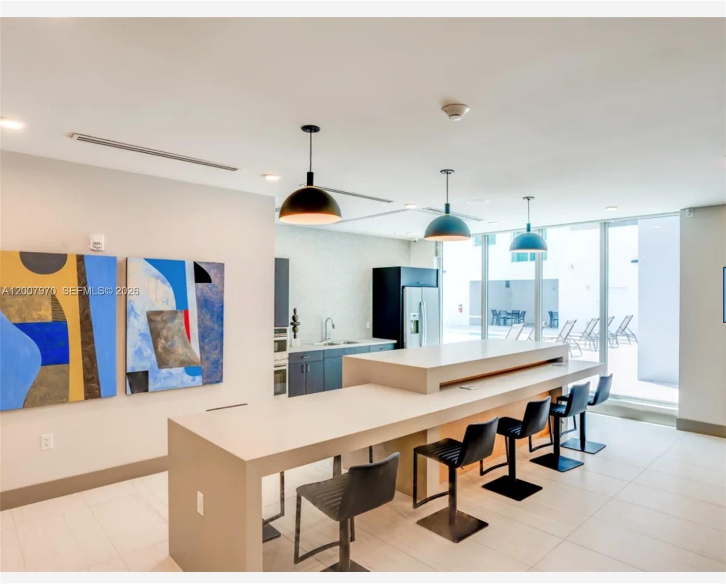 A modern kitchen area features a long island with bar stools and hanging pendant lights — 61 NW 37th Ave # 01, Miami FL 33125, MIAMI, FL