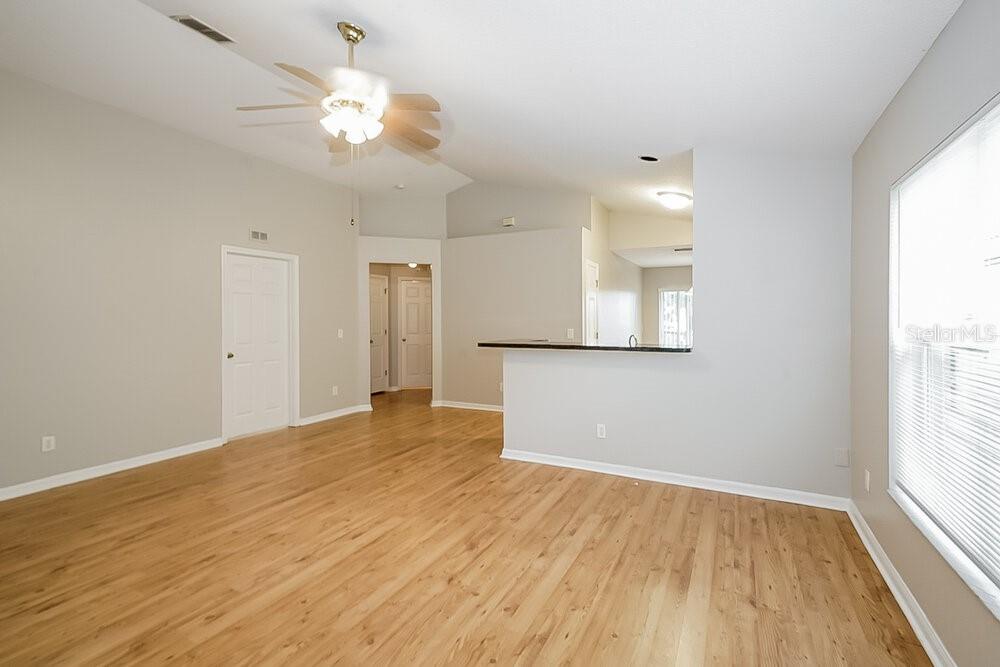 An open-concept living room features light wood flooring, a ceiling fan, and a breakfast bar — 7445 OXFORD GARDEN CIRCLE, APOLLO BEACH, FL